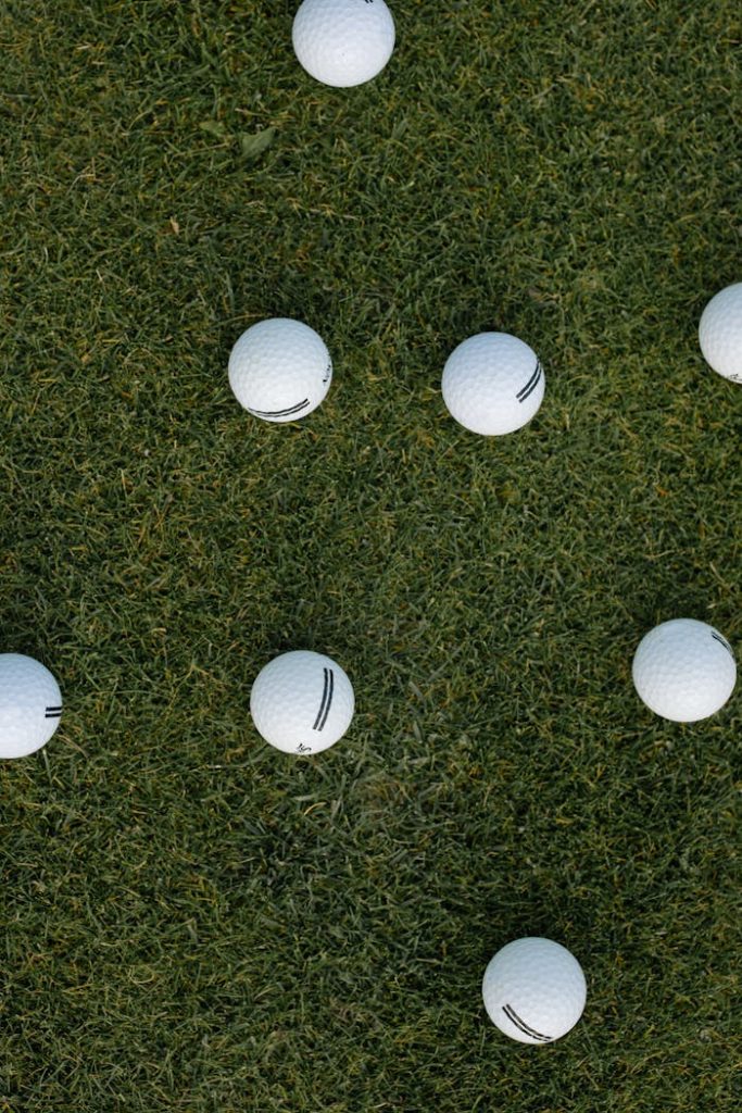 Scattered golf balls on lush green grass viewed from above, offering an ideal sports background.